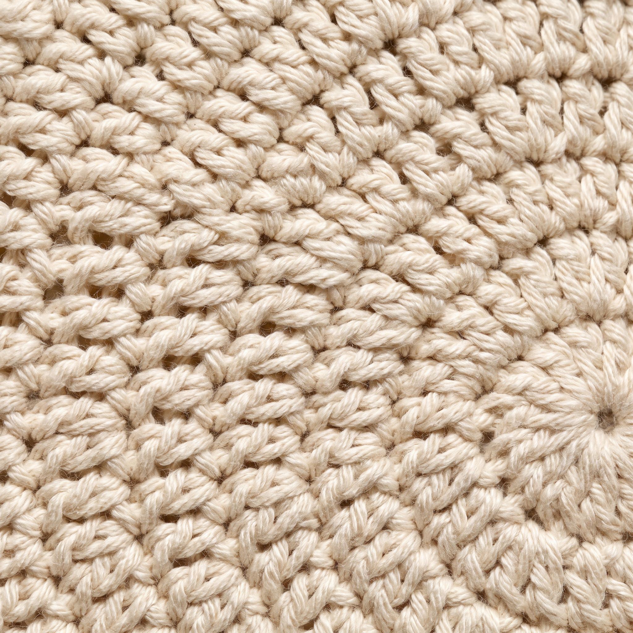 Extreme close-up of hand-crocheted cream cotton stitches showing the texture of genuine handwork